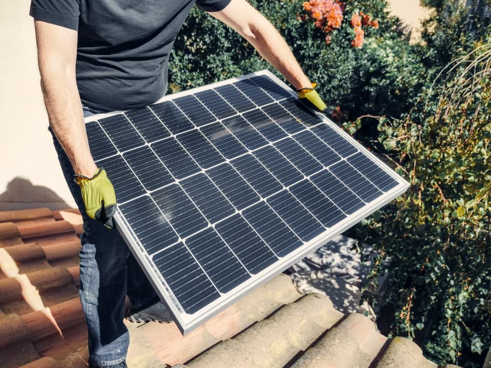 Solar installer mounting a solar panel on a Baghdad rooftop